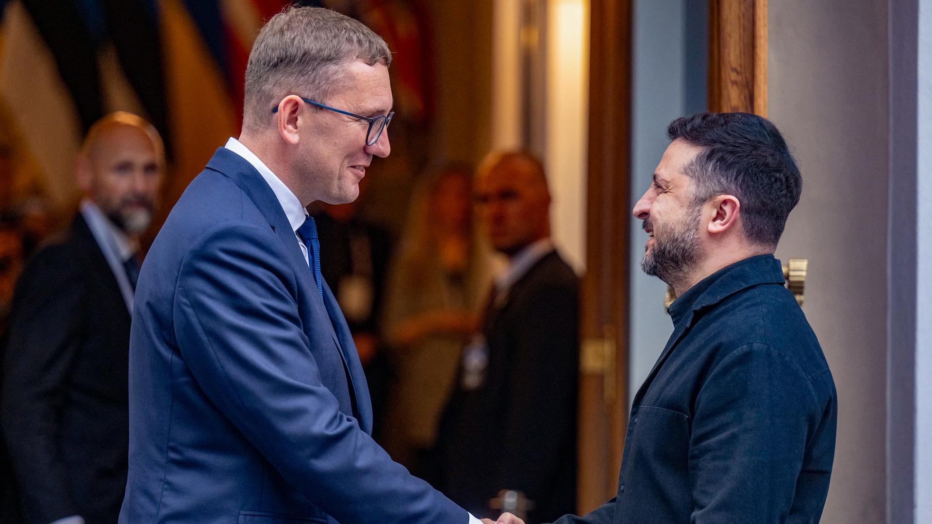 Ministerpräsident Michal und Präsident Selenskyj geben sich die Hand. Sie schauen sich an und lächeln. Im Hintergrund ist eine geöffnete Tür zu erkennen. Ministerpräsident Michal und Präsident Selenskyj geben sich die Hand. Sie schauen sich an und lächeln. Im Hintergrund ist eine geöffnete Tür zu erkennen.