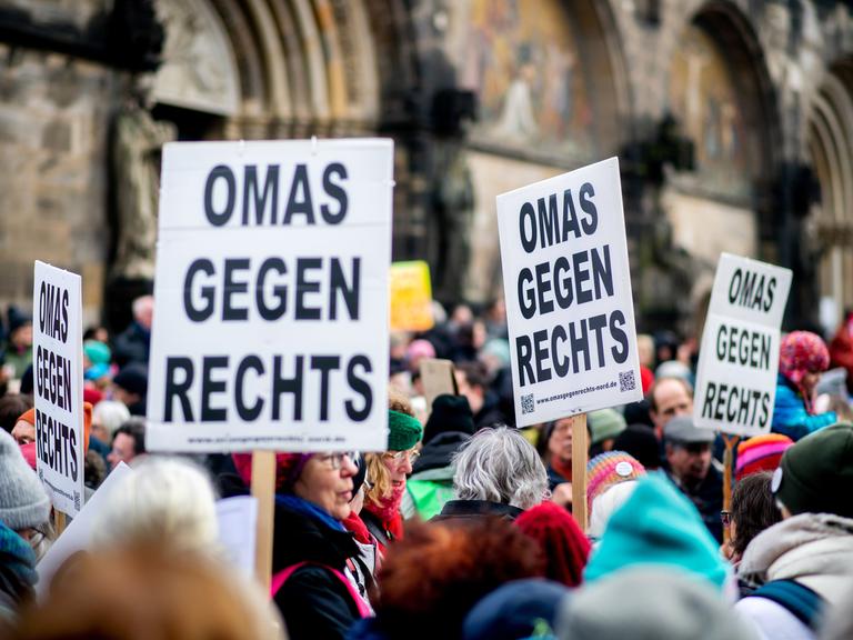 Zahlreiche Menschen stehen dicht gedrängt auf einer Demonstration. Mehrere Teilnehmer halten Schilder mit der Aufschrift "Omas gegen Rechts" hoch.