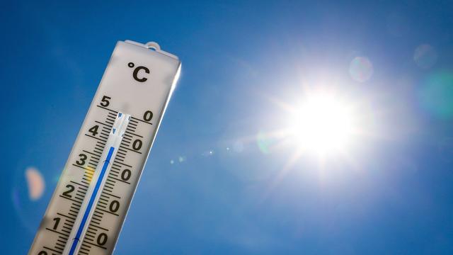 Ein Thermometer vor blauem Himmel mit gleißender Sonne. Das Thermometer zeigt 39 Grad an. 