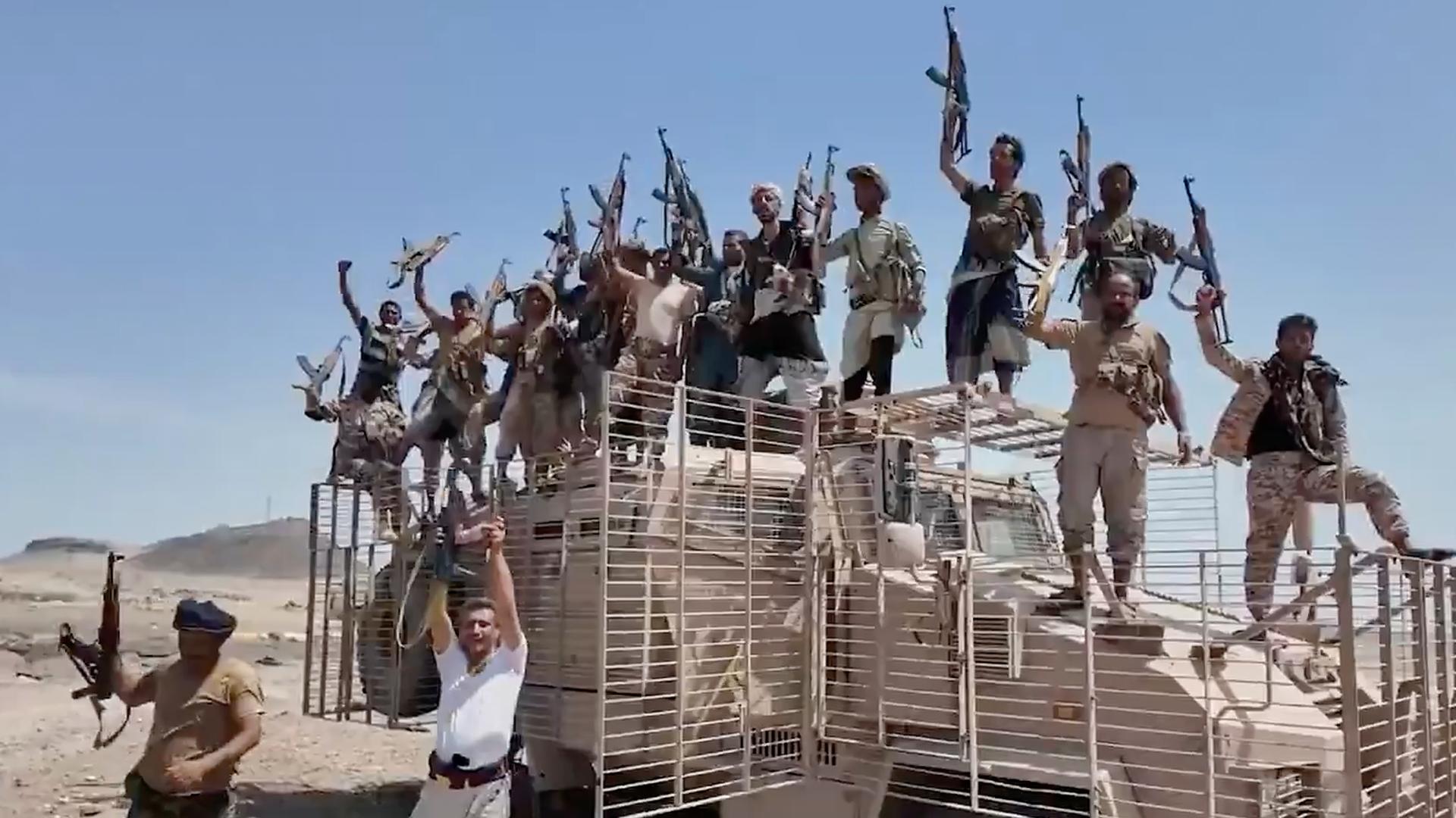 Huthi-Kämpfer stehen auf einem Last-Wagen. Sie halten ihre Gewehre in die Höhe. Huthi-Kämpfer stehen auf einem Last-Wagen. Sie halten ihre Gewehre in die Höhe.