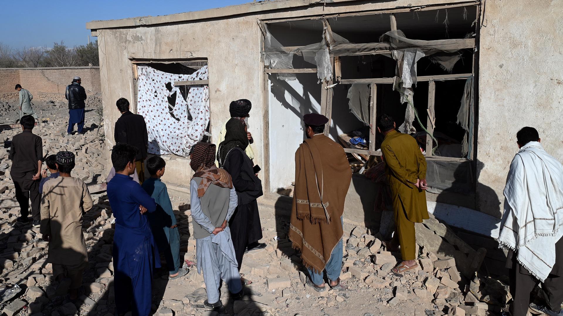 Afghanen inspizieren ein zerstörtes Haus.