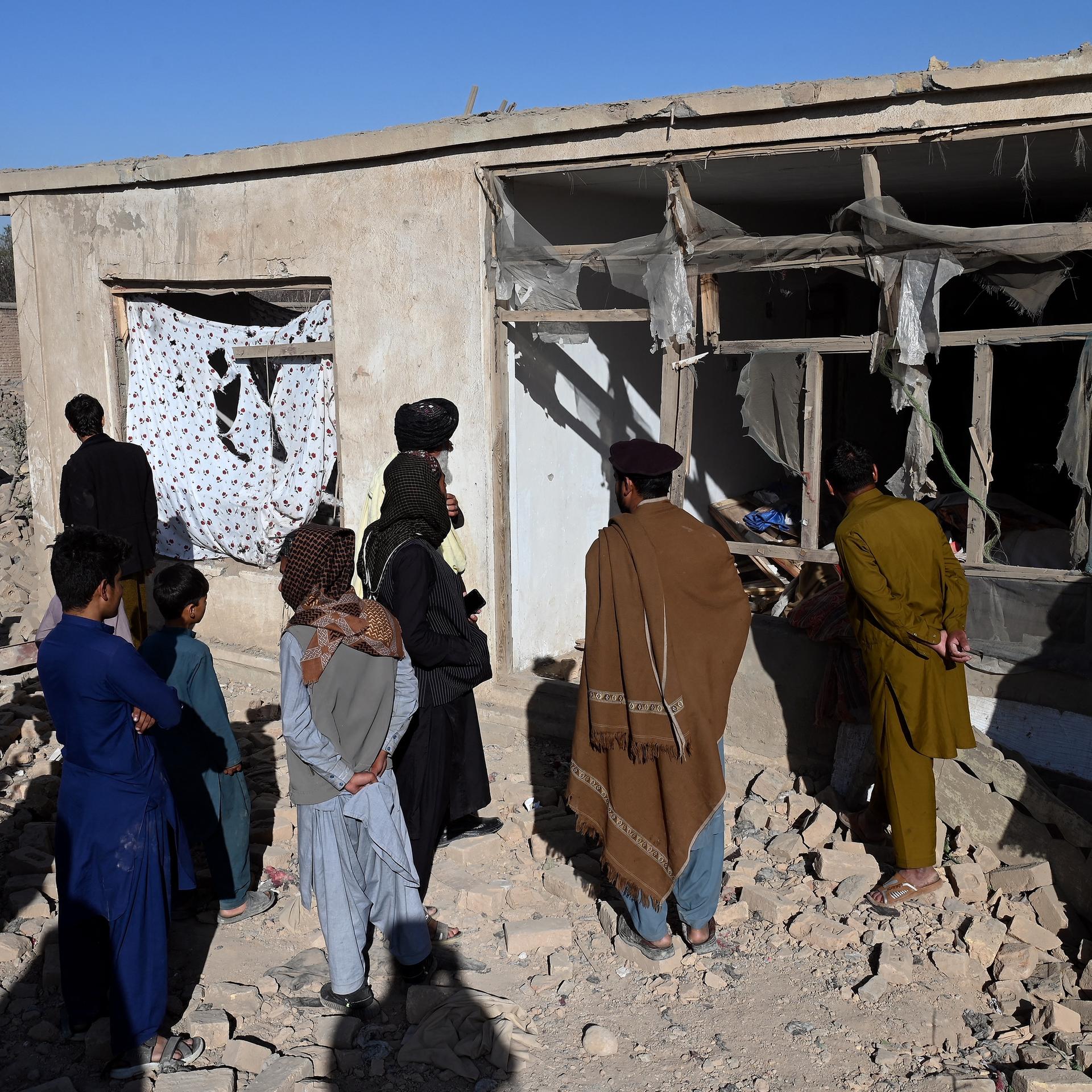 Afghanen inspizieren ein zerstörtes Haus.