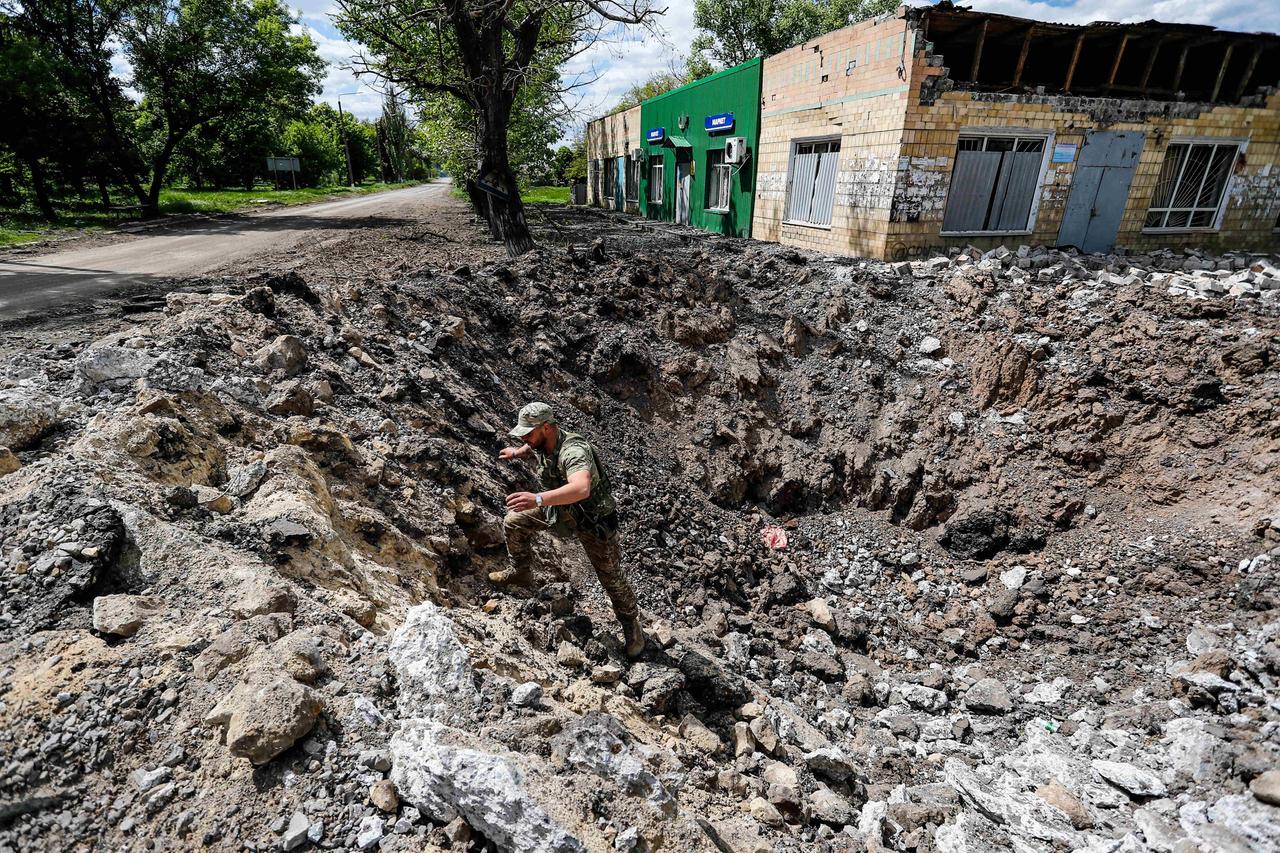Ein ukrainischer Soldat steht in einem riesigen Krater neben einer Straße, das durch einen russischen Luftangriff entstanden sein soll. 