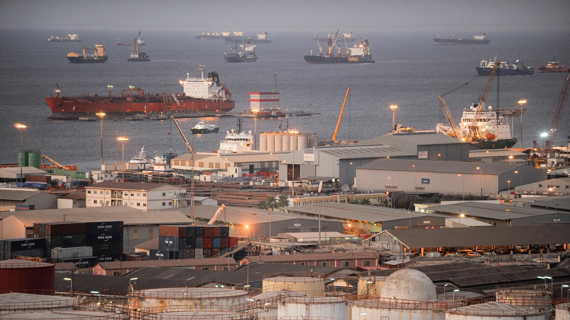 Öltanker liegen in Angola vor Anker. Im Vordergrund sind Bauten des nationalen Ölunternehmens des Landes zu sehen.