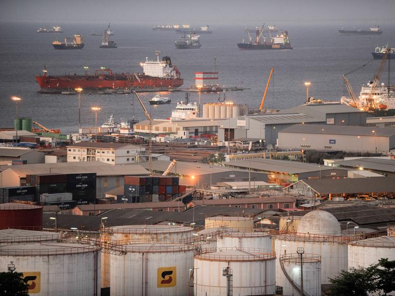 Öltanker liegen in Angola vor Anker. Im Vordergrund sind Bauten des nationalen Ölunternehmens des Landes zu sehen.