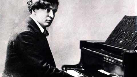 Eine undatierte Schwarz-Weiß-Fotografie zeigt den Komponisten, Pianisten und Dirigenten Ferruccio Busoni (1866-1924), wie er an einem Klavier sitzt.