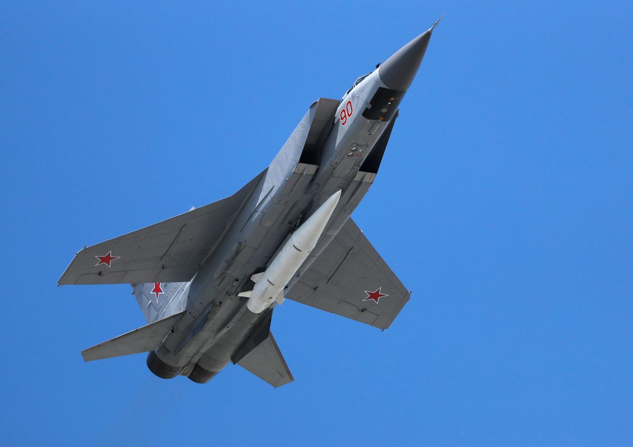 Ein russisches Militärflugzeug in der Luft. Am Rumpf ist eine weiße Rakete befestigt.