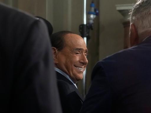 Silvio Berlusconi - lachend zwischen zwei weiteren Männern