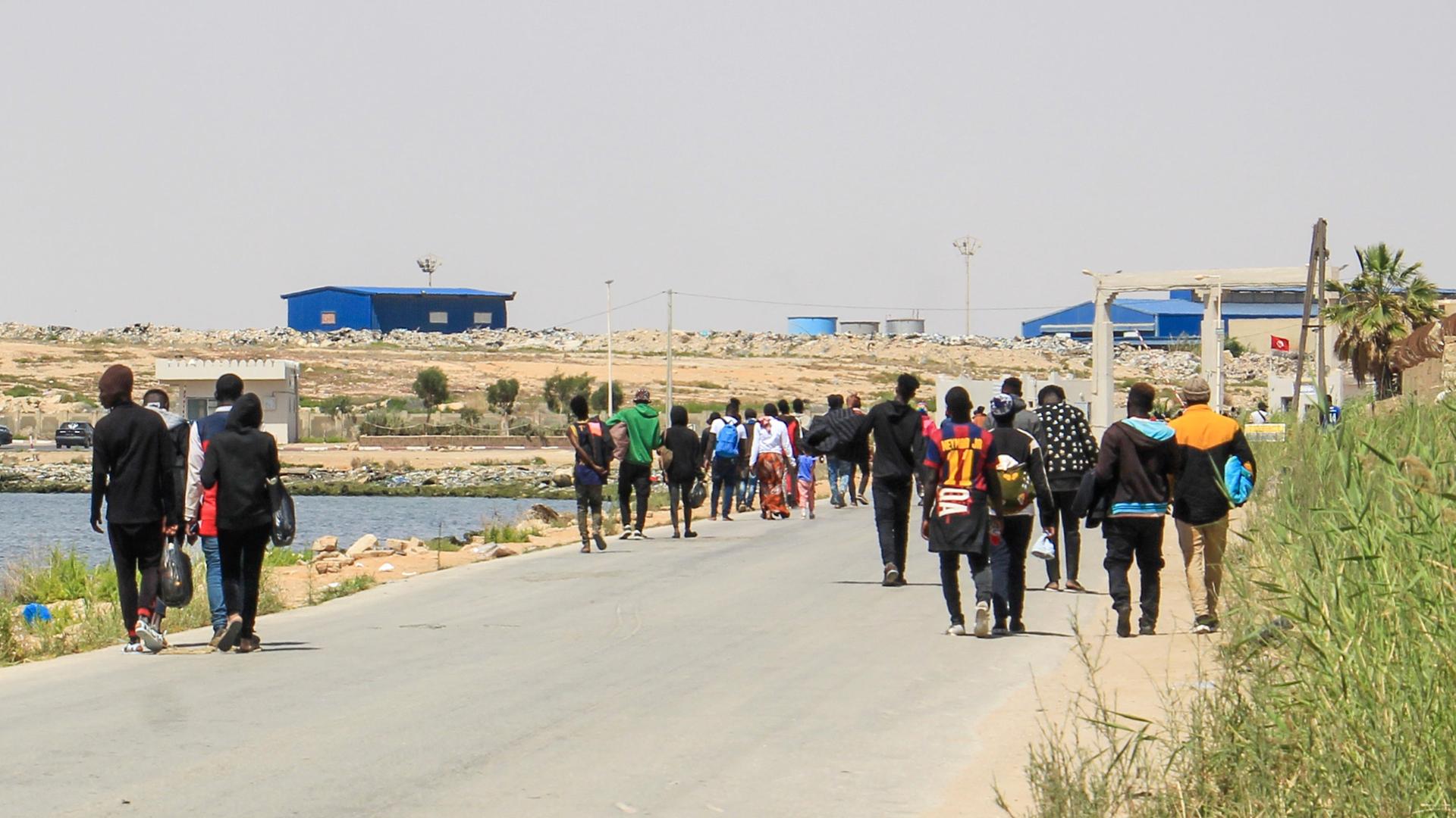 Migranten, die von tunesischen Einsatzkräften auf dem Meer aufgespürt wurden, gehen eine Strasse hinunter, nachdem sie am Hafen zurück an Land gelassen wurden.