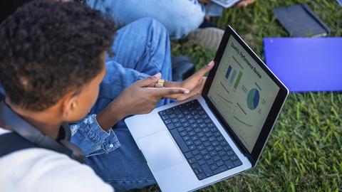 Studenten arbeiten gemeinsam an einem Projekt und analysieren Daten zur Leistungsbewertung und Marktanteilsdiagramme auf einem Laptop-Bildschirm