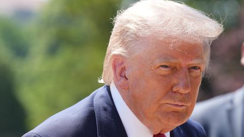 Ein Portrait von US-Präsident Donald Trump. Trump sieht zur Seite, im Hintergrund sind unscharf Bäume zu sehen.