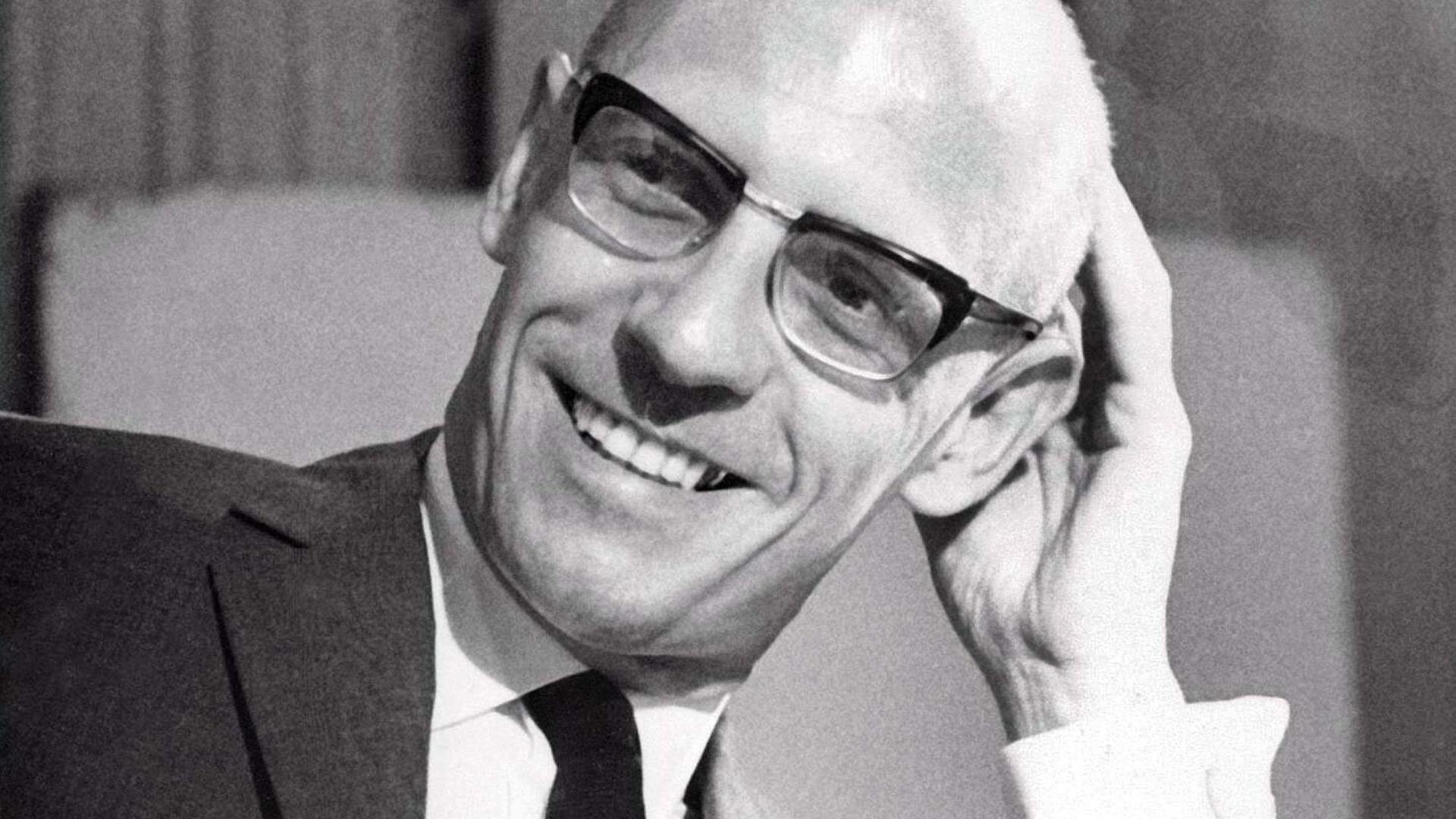 Schwarzweiß-Porträt von Michel Foucault an seinem Schreibtisch