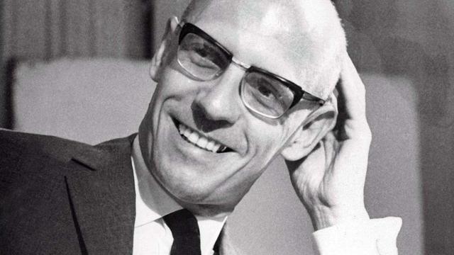 Schwarzweiß-Porträt von Michel Foucault an seinem Schreibtisch