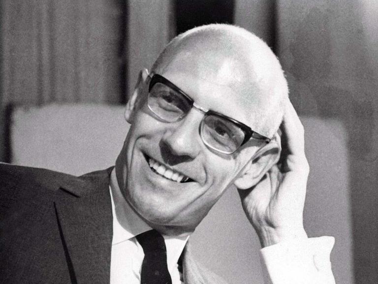 Schwarzweiß-Porträt von Michel Foucault an seinem Schreibtisch