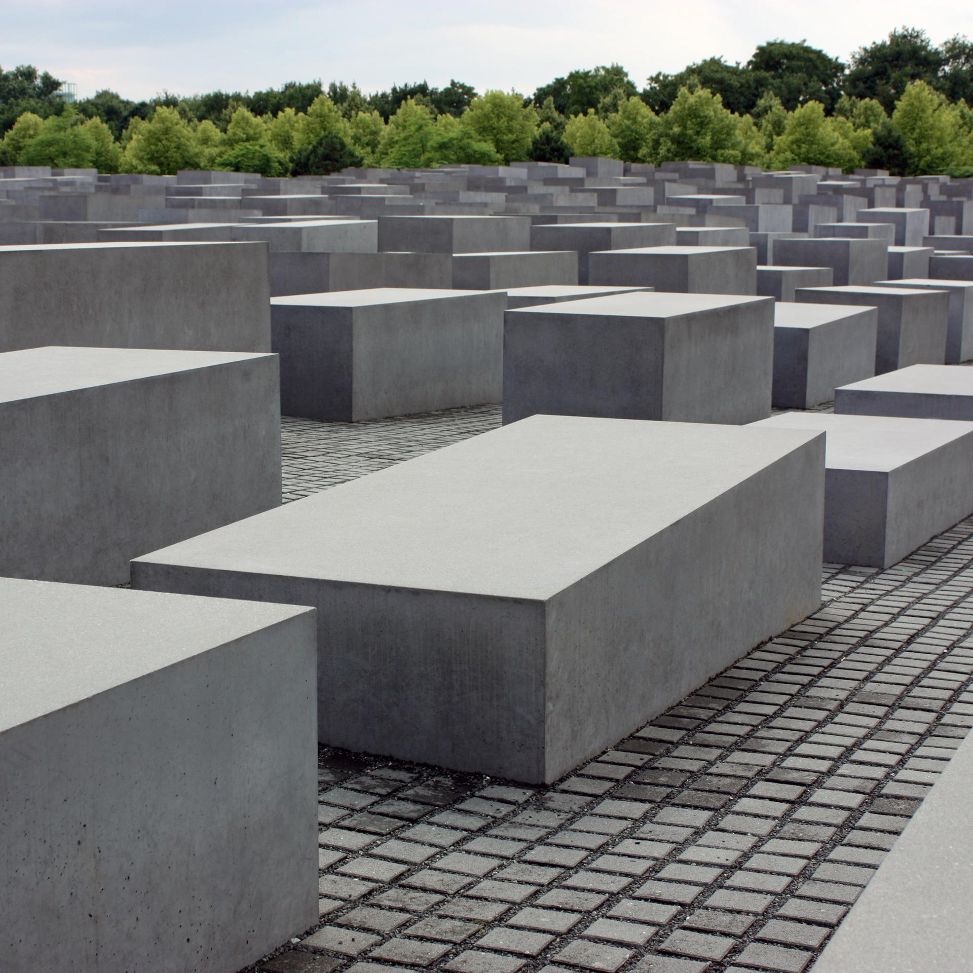 Die grauen Stehlen des Holocaust-Mahnmals in Berlin stehen auf einem großen, gepflasterten Platz.