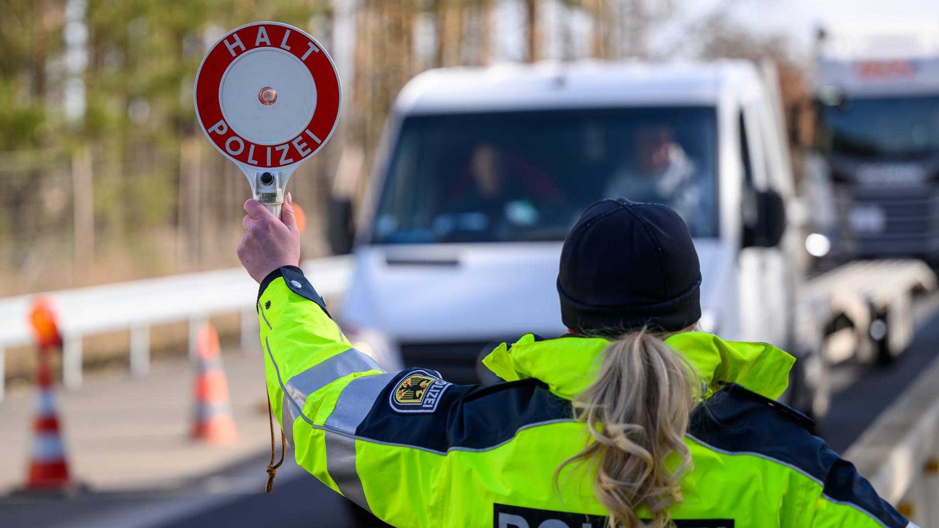 Eine deutsche Polizistin stoppt ein Auto an der Grenze zu dem Land Polen.