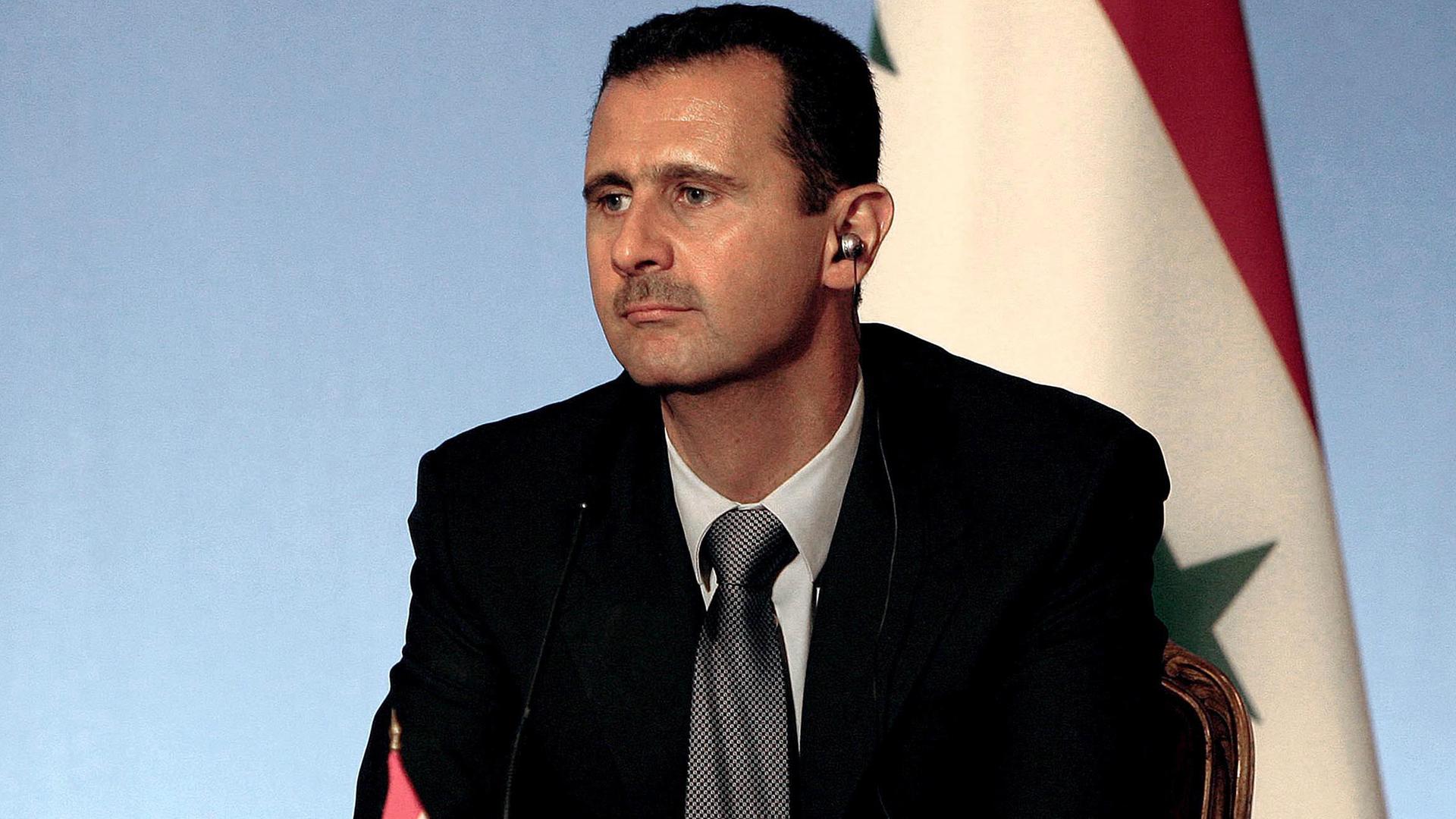 Der syrische Präsident Bashar Al-Assad vor einer Landesflagge