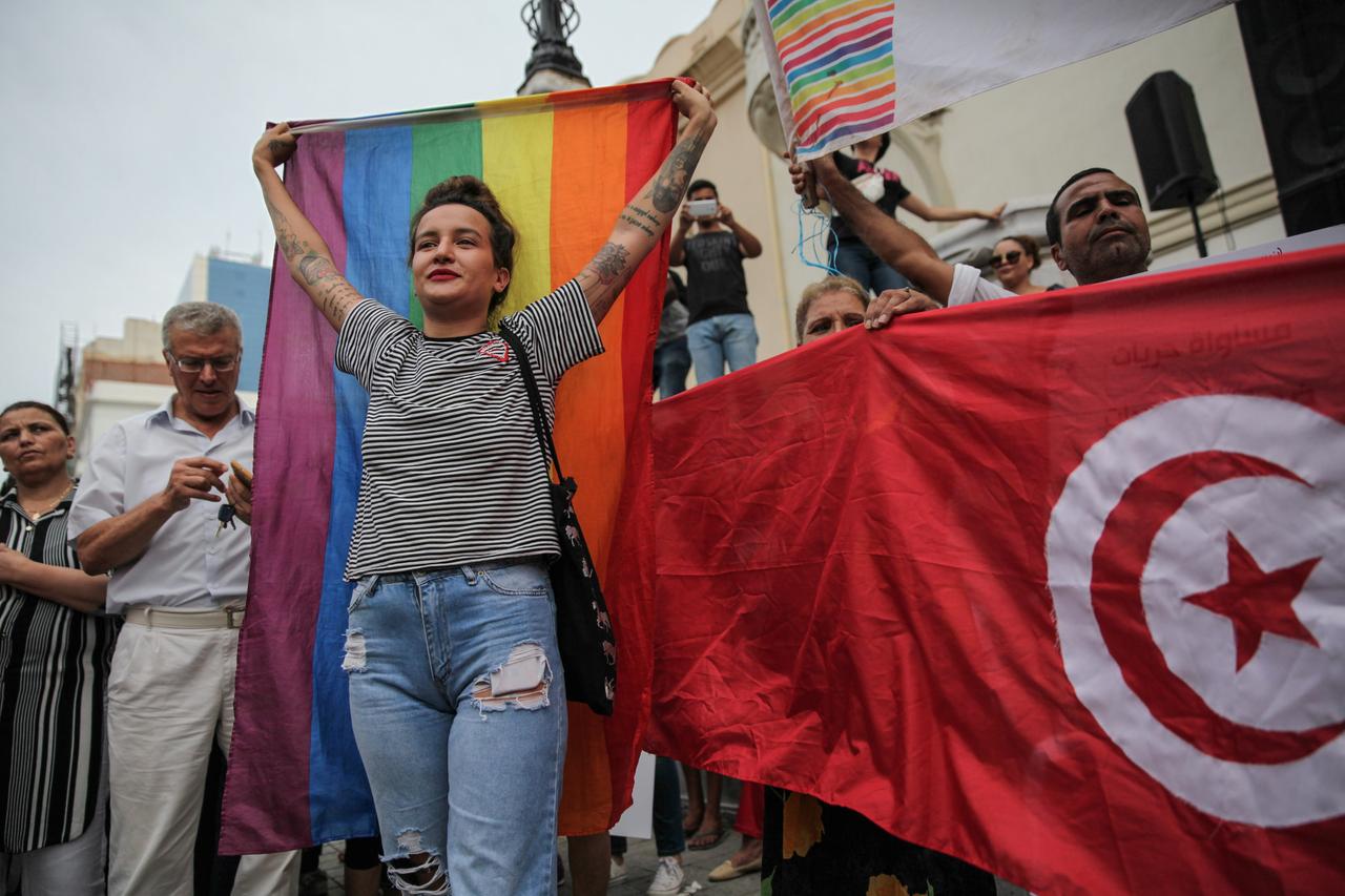 Amina Sboui, ehemalige Femen, hält bei einer Demonstration am Nationalen Frauentag im August 2018 in Tunis eine Regenbogenflagge hoch. Daneben sind weitere Demonstranten mit der tunesischen Flagge zu sehen.