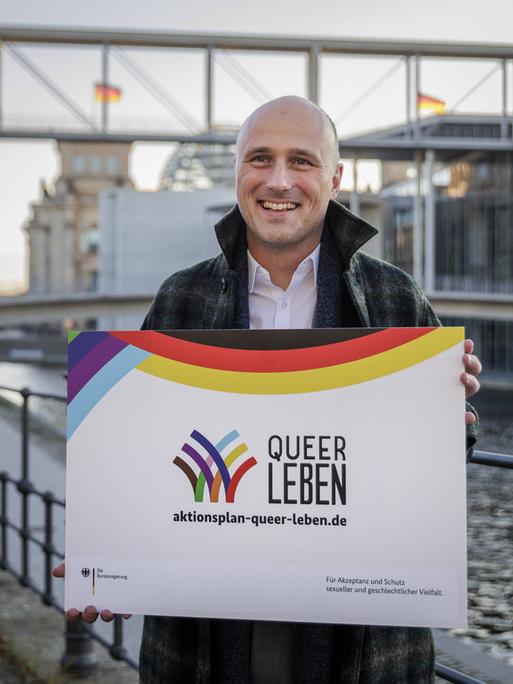 Der Queer-Beauftragte Sven Lehmann (Grüne) steht im Regierungsviertel mit einem Transparent zum Aktionsplan "Queer Leben". 