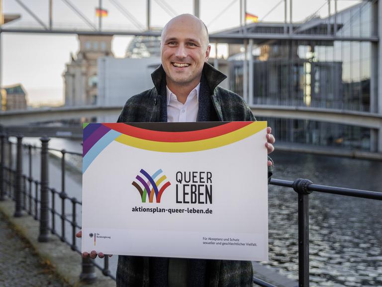 Der Queer-Beauftragte Sven Lehmann (Grüne) steht im Regierungsviertel mit einem Transparent zum Aktionsplan "Queer Leben". 