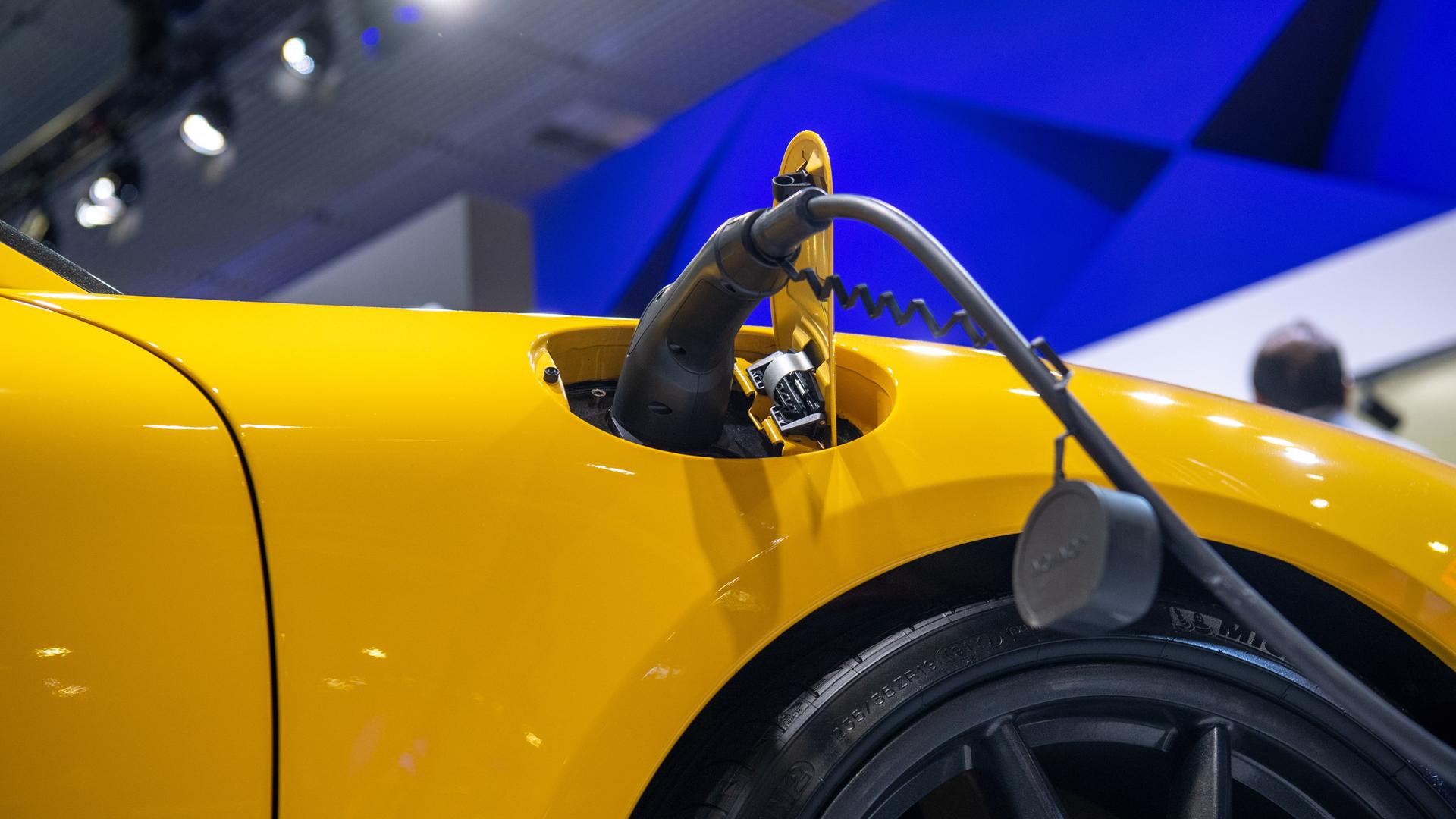 Ein E-Auto wird aufgeladen während der IFA in Berlin. Ein Ladestecker steckt in einem gelben Auto.