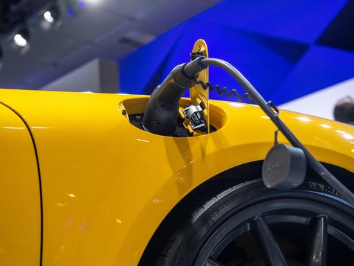 Ein E-Auto wird aufgeladen während der IFA in Berlin. Ein Ladestecker steckt in einem gelben Auto.