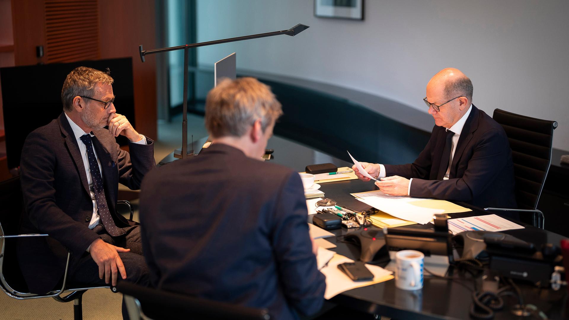 Das von der Bundesregierung veröffentlichte Bild zeigt Bundeskanzler Scholz in seinem Büro bei einem Telefonat mit Russlands Präsident Putin. Neben Scholz sitzen der außen- und sicherheitspolitische Berater Plötner und Regierungssprecher Hebestreit.