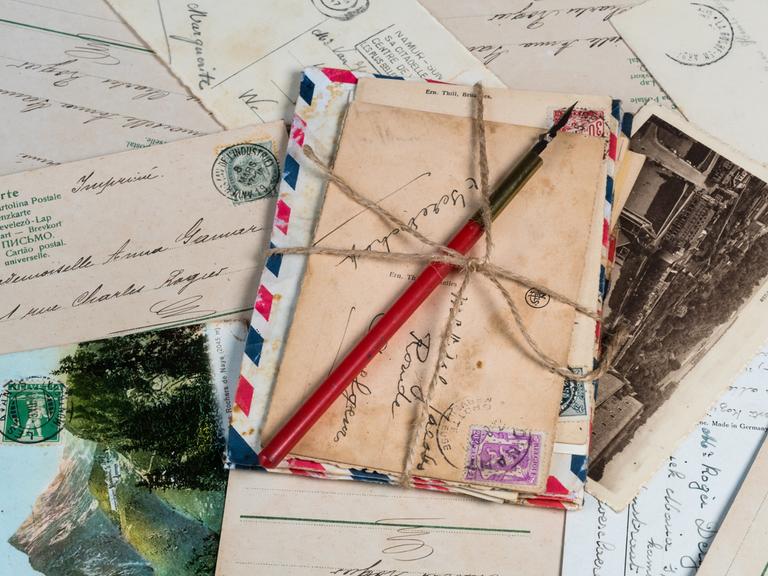 Blick auf einen gebündelten Stapel von Briefen, der auf anderen Kuverts und Postkarten liegt.