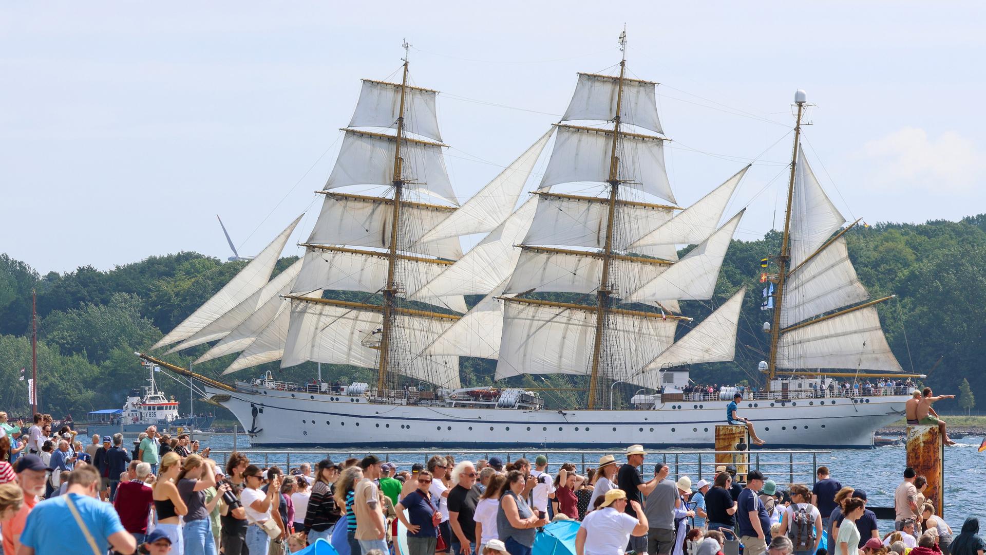 Das Segelschulschiff "Gorch Fock" startet bei der traditionellen Windjammerparade auf der Kieler Förde. Am Ufer zahlreiche Zuschauer 