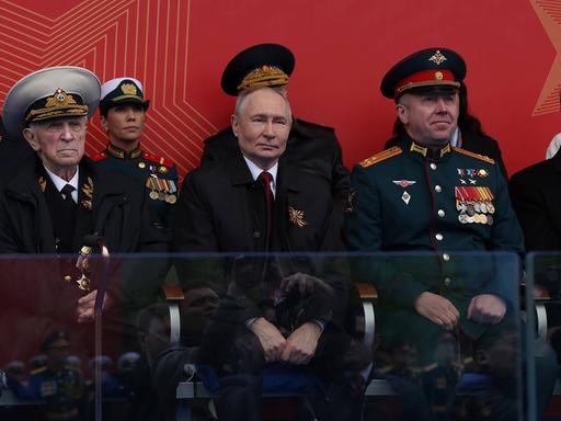 Der russische Präsident Wladimir Putin verfolgt, umringt von Gästen, die Parade, die an den Sieg der Sowjetunion über das NS-Regime vor 81 Jahren erinnert.
Der russische Präsident Wladimir Putin verfolgt, umringt von Gästen, die Parade, die an den Sieg der Sowjetunion über das NS-Regime vor 81 Jahren erinnert.