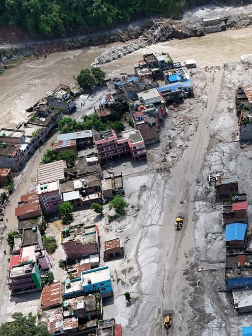 Luftaufnahme einer Ortschaft in Nepal, die von einer schlammigen Sturzflut überschwemmt wurde. Zahlreiche Häuser sind schwer beschädigt oder fortgerissen. Luftaufnahme einer Ortschaft in Nepal, die von einer schlammigen Sturzflut überschwemmt wurde. Zahlreiche Häuser sind schwer beschädigt oder fortgerissen.