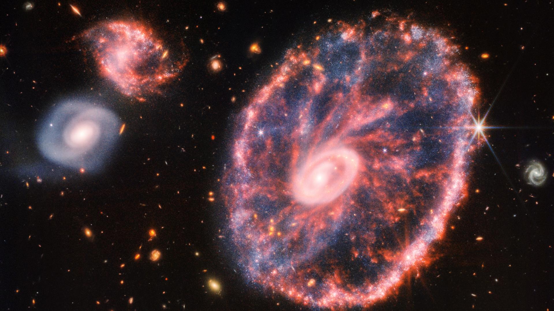 Drama in 500 Millionen Lichtjahren Entfernung: Die kleine pinkfarbene Galaxie ist durch die große hindurchgeflogen - dabei ist der markante Sternring entstanden. Die anderen Objekte sind zufällig mit im Blickfeld. Drama in 500 Millionen Lichtjahren Entfernung: Die kleine pinkfarbene Galaxie ist durch die große hindurchgeflogen - dabei ist der markante Sternring entstanden. Die anderen Objekte sind zufällig mit im Blickfeld.