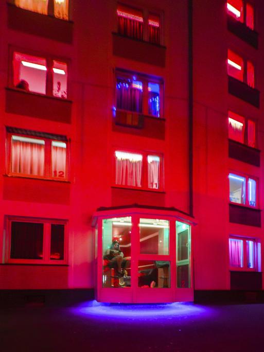Das Foto zeigt ein rot beleuchtetes Bordell mit Prostituierten in den Fenstern in Düsseldorf.