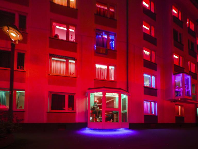 Das Foto zeigt ein rot beleuchtetes Bordell mit Prostituierten in den Fenstern in Düsseldorf.