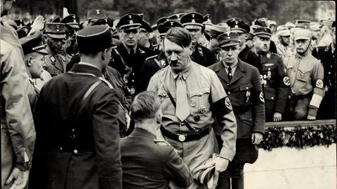 Schwarz-Weiß-Fotografie: Auf dem Nürnberger Reichsparteitag ist Adolf Hitler im Gespräch mit einem Veteranen, daneben Männer von der SS und SA