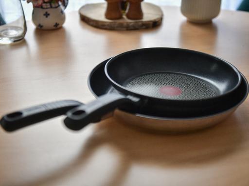 Zwei beschichtete Pfannen des Herstellers Tefal stehen auf einem Tisch.