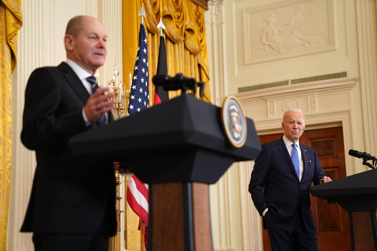 Bundeskanzler Olaf Scholz und US-Präsident Joe Biden stehen im Weißen Haus während einer Pressekonferenz an zwei Pulten. Scholz redet, während Biden ihm zuhört.
