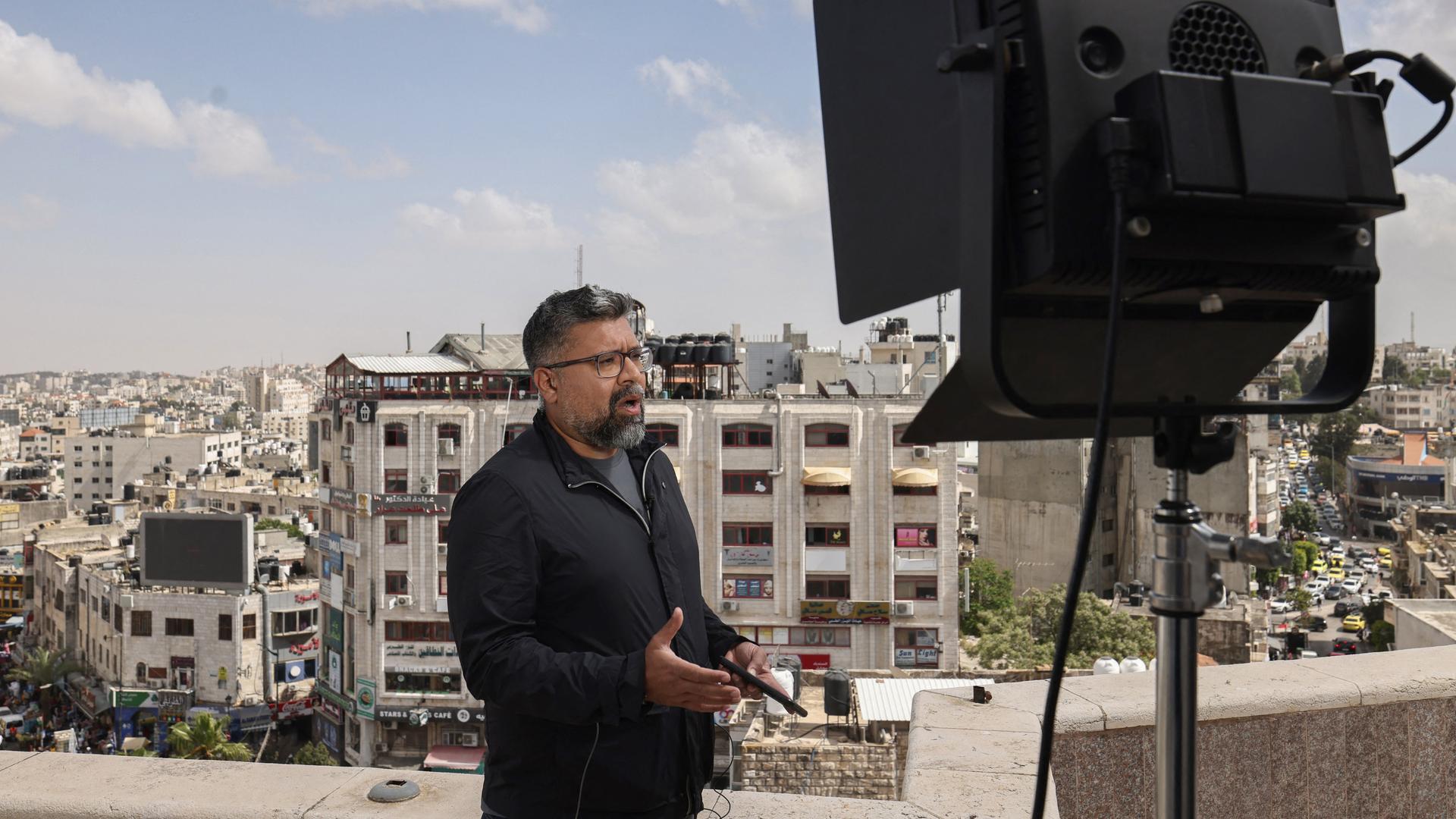 Ein Korrespondent steht während einer Live-Sendung auf einem Dach in Ramallah und spricht, im Hintergrund sind die Dächer der Stadt zu sehen.