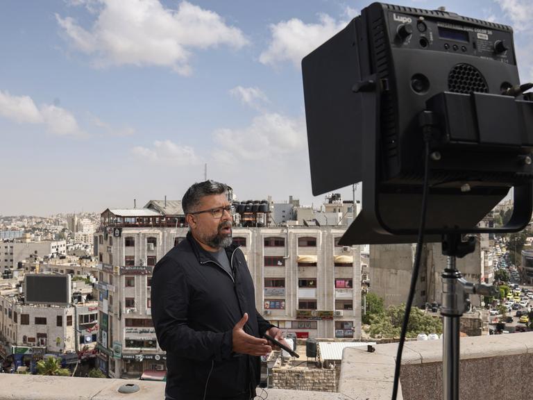 Ein Korrespondent steht während einer Live-Sendung auf einem Dach in Ramallah und spricht, im Hintergrund sind die Dächer der Stadt zu sehen.