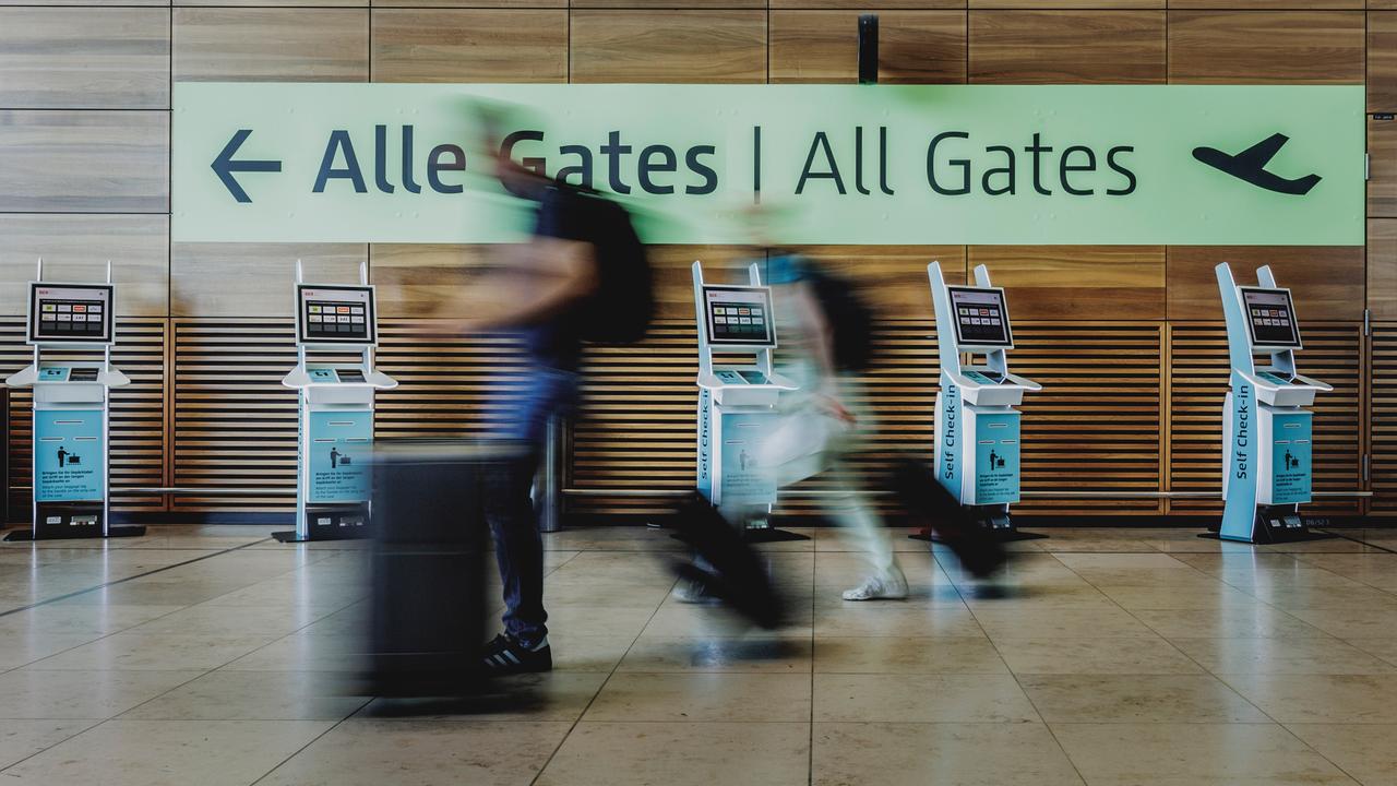 Verschwommene Personen gehen am Flughafen yum Abfluggate.