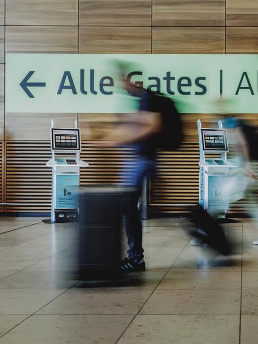 Verschwommene Personen gehen am Flughafen yum Abfluggate.