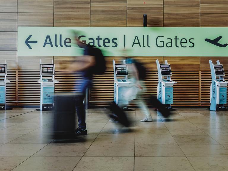 Verschwommene Personen gehen am Flughafen yum Abfluggate.