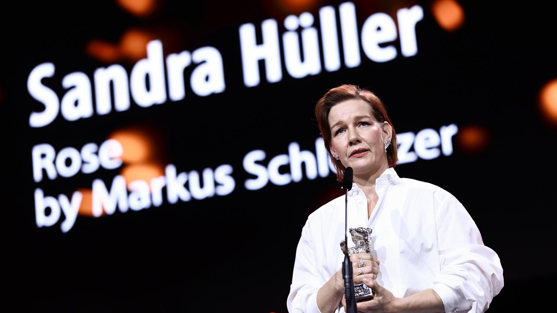 Sandra Hüller hält den Silbernen Bären in der Hand. Sie steht vor einem Mikrofon. 