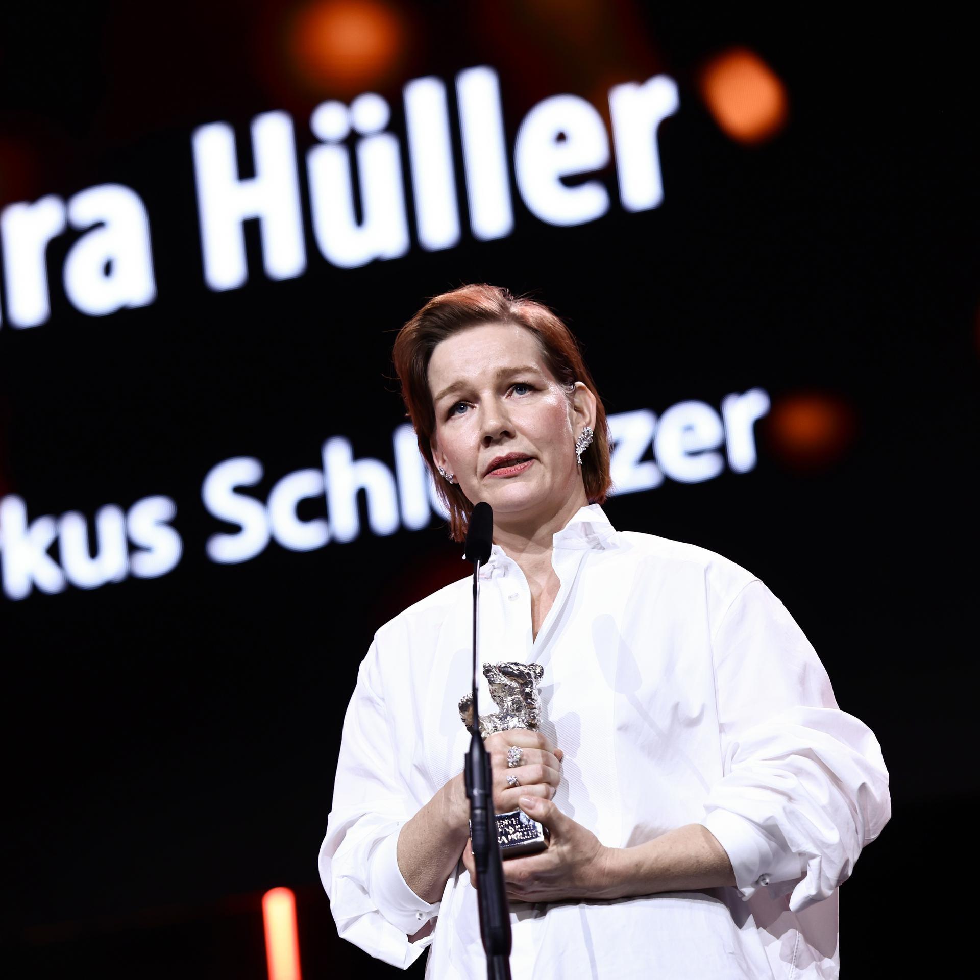 Sandra Hüller hält den Silbernen Bären in der Hand. Sie steht vor einem Mikrofon. 