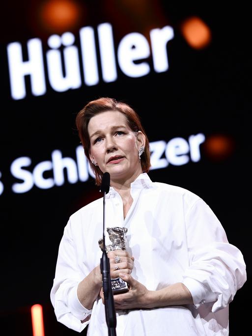 Sandra Hüller hält den Silbernen Bären in der Hand. Sie steht vor einem Mikrofon. 