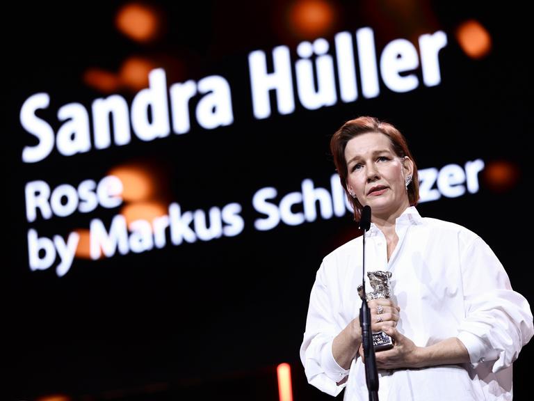 Sandra Hüller hält den Silbernen Bären in der Hand. Sie steht vor einem Mikrofon. 