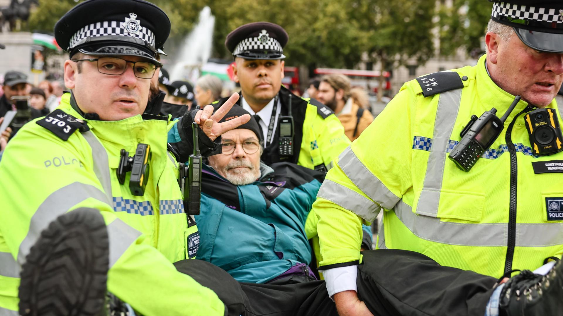 Das Bild zeigt zwei britische Polizisten, die einen Unterstützer der Organisation "Palestine Action" festnehmen und wegtragen. 