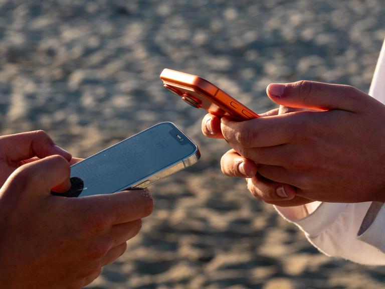 Die Hände von zwei Jugendlichen, die jeweils auf einem Mobiltelefon scrollen Die Hände von zwei Jugendlichen, die jeweils auf einem Mobiltelefon scrollen