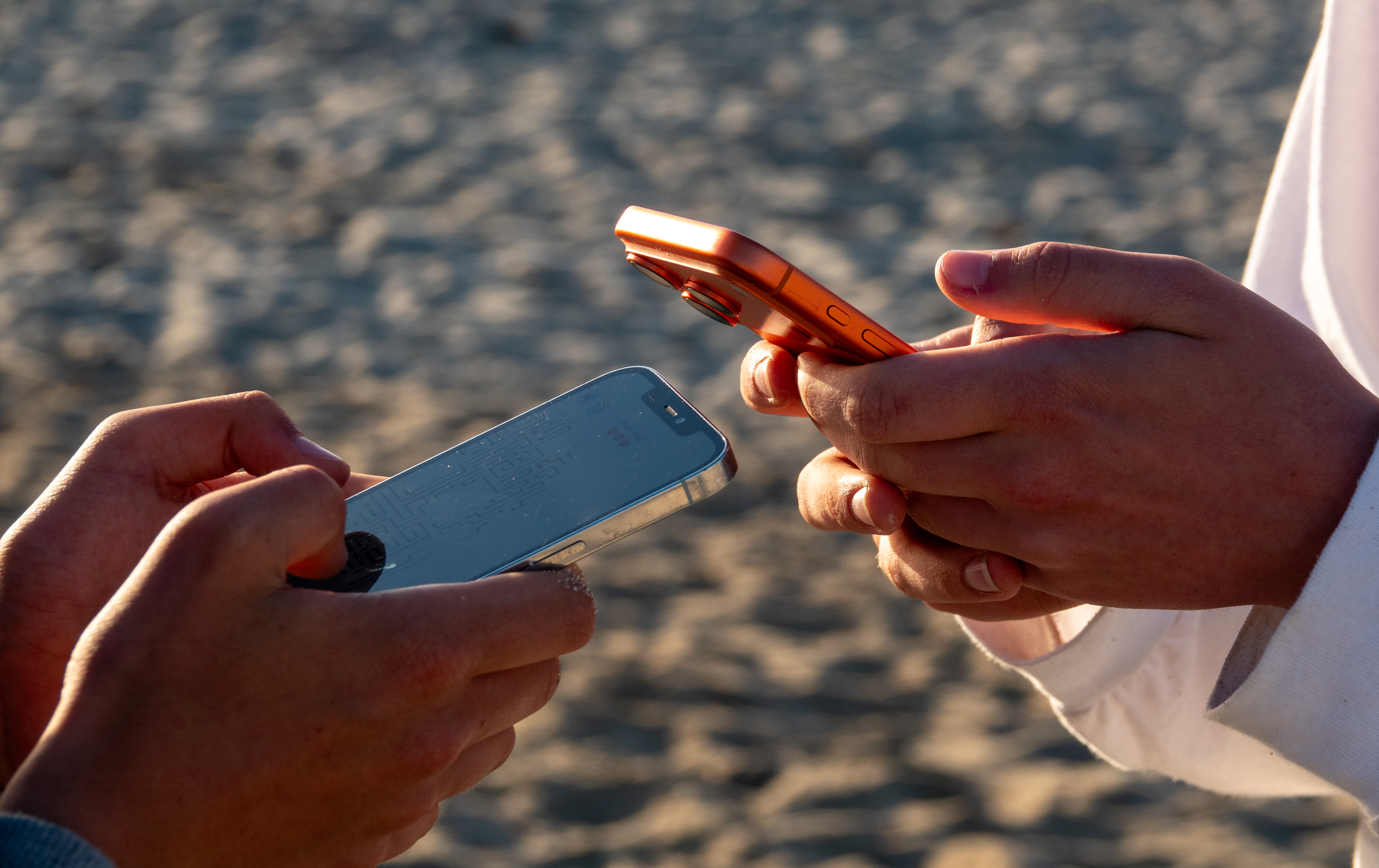 Die Hände von zwei Jugendlichen, die jeweils auf einem Mobiltelefon scrollen Die Hände von zwei Jugendlichen, die jeweils auf einem Mobiltelefon scrollen