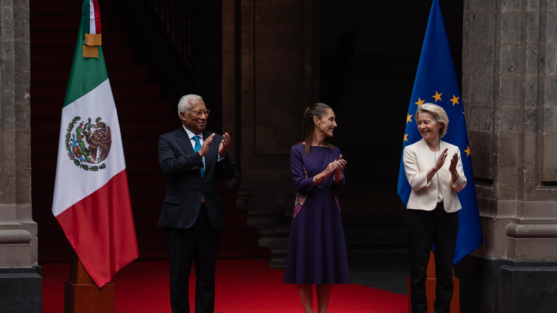 Die mexikanische Präsidentin Claudia Sheinbaum (M.) begrüßt EU-Ratspräsident António Costa und die EU-Kommissionspräsidentin Ursula von der Leyen im Präsidentenpalast. Sie sind festlich gekleidet, lächeln sich freundlich an und klatschen in die Hände. Die mexikanische Präsidentin Claudia Sheinbaum (M.) begrüßt EU-Ratspräsident António Costa und die EU-Kommissionspräsidentin Ursula von der Leyen im Präsidentenpalast. Sie sind festlich gekleidet, lächeln sich freundlich an und klatschen in die Hände.